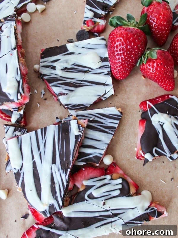 Pieces of chocolate peanut butter strawberry bark on brown parchment paper.