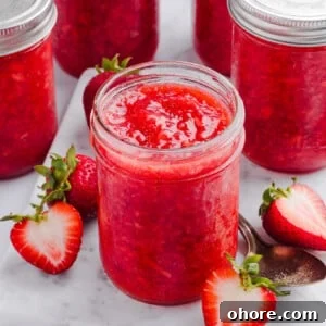 Low sugar strawberry freezer jam in jars on a marble slab.