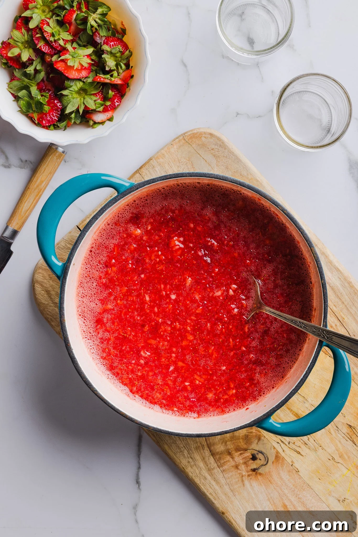 Fresh strawberries mixed with sugar and pectin in a saucepan.