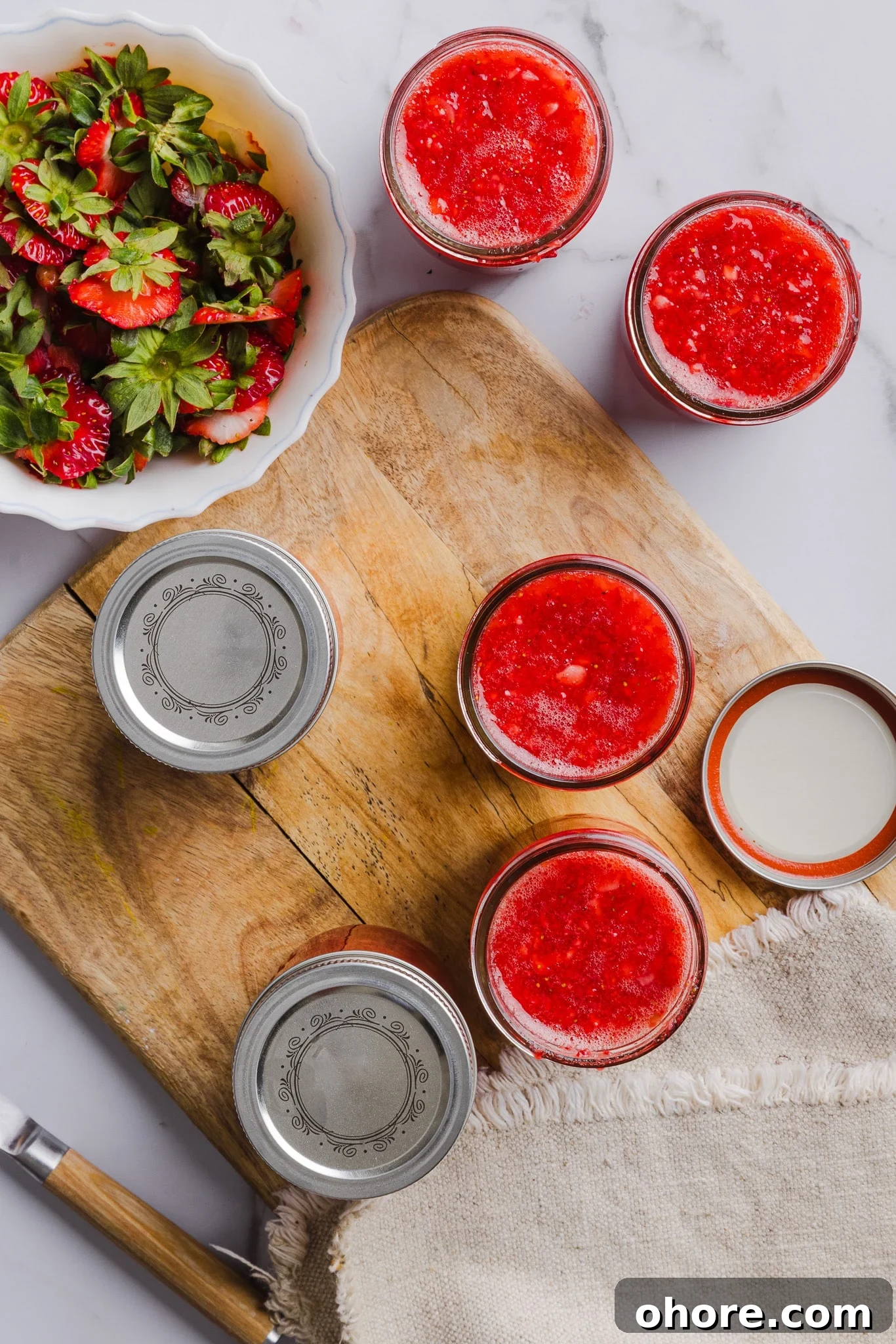 Low sugar strawberry freezer jam in jars on a wooden board.