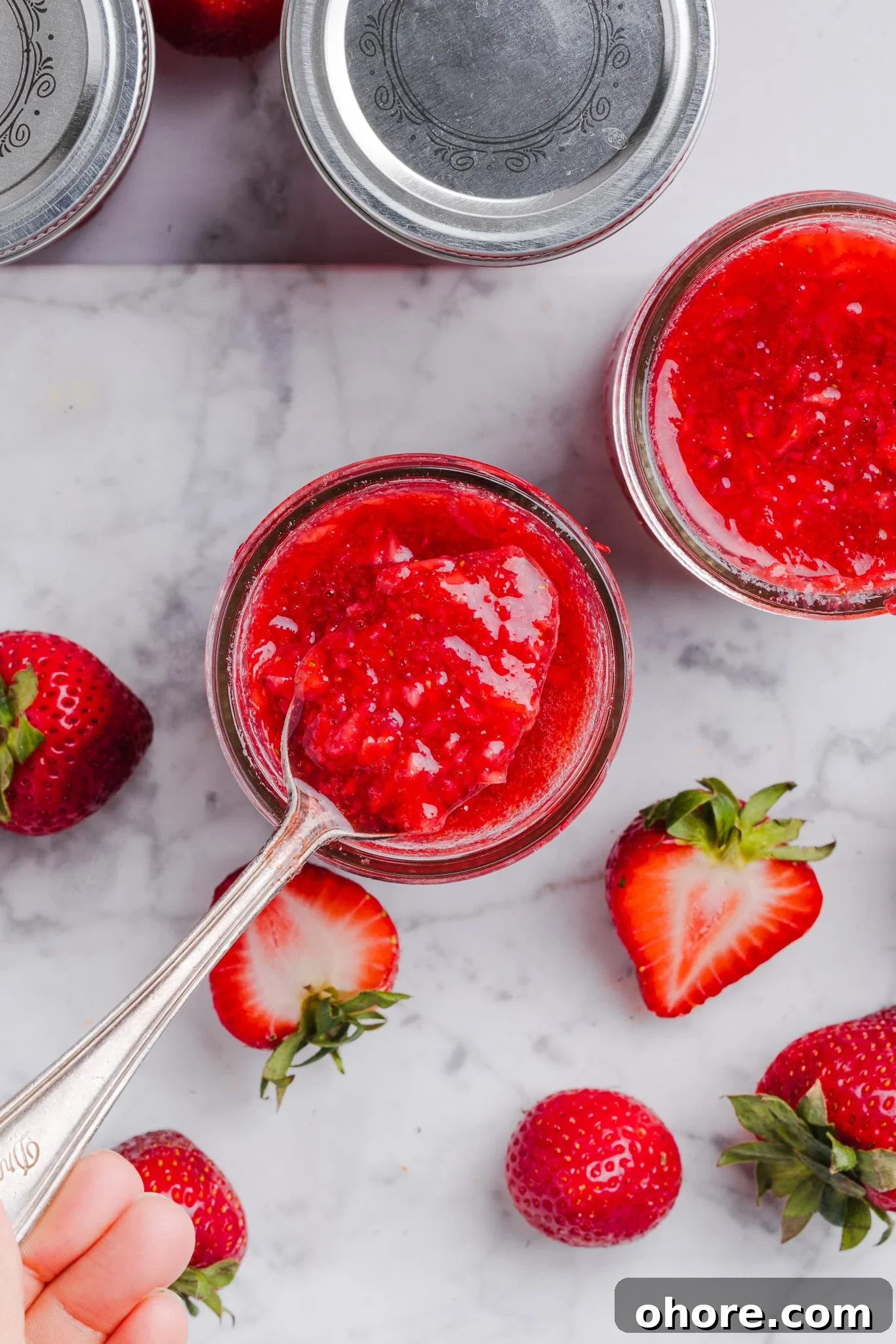 A spoonful of low sugar strawberry freezer jam above a jar. 