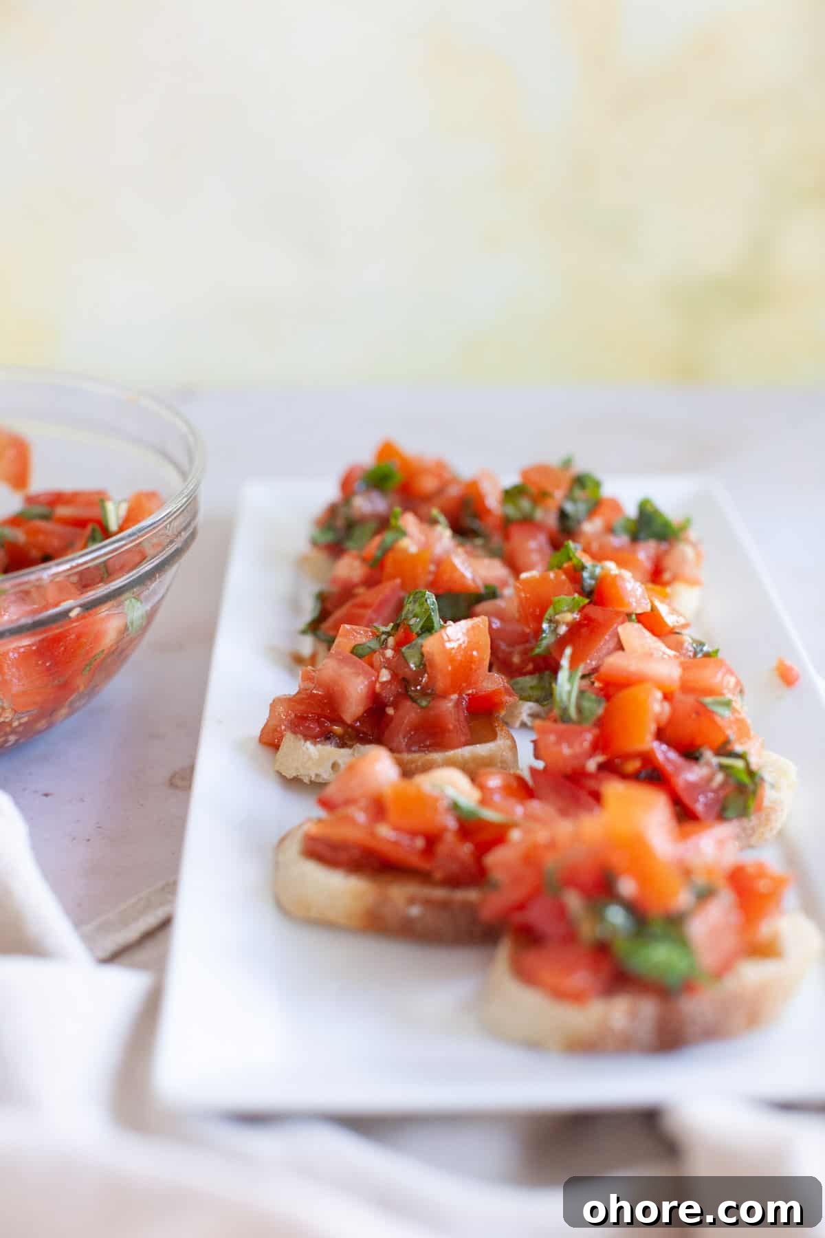 Wide photo of bruschetta placed on a rectangular serving dish.