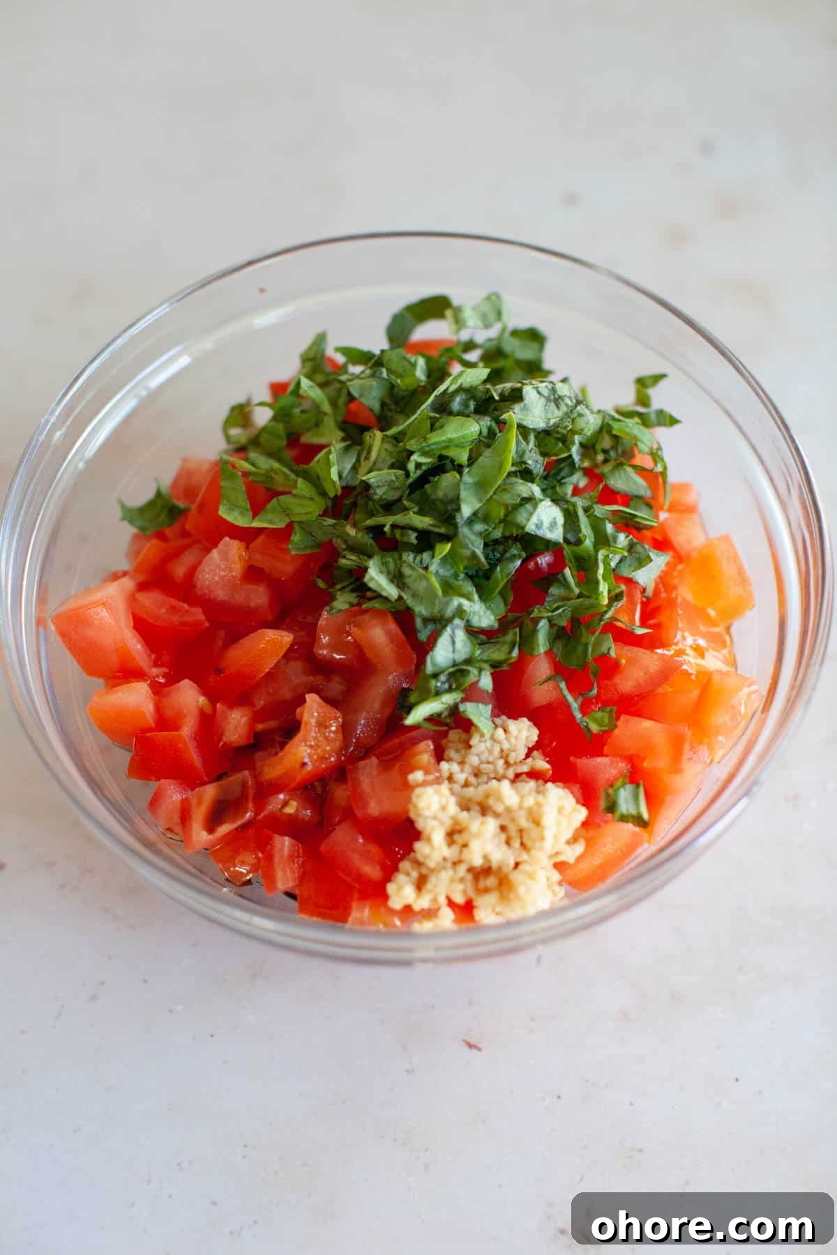 Bruschetta ingredients, unmixed, placed in a glass bowl.