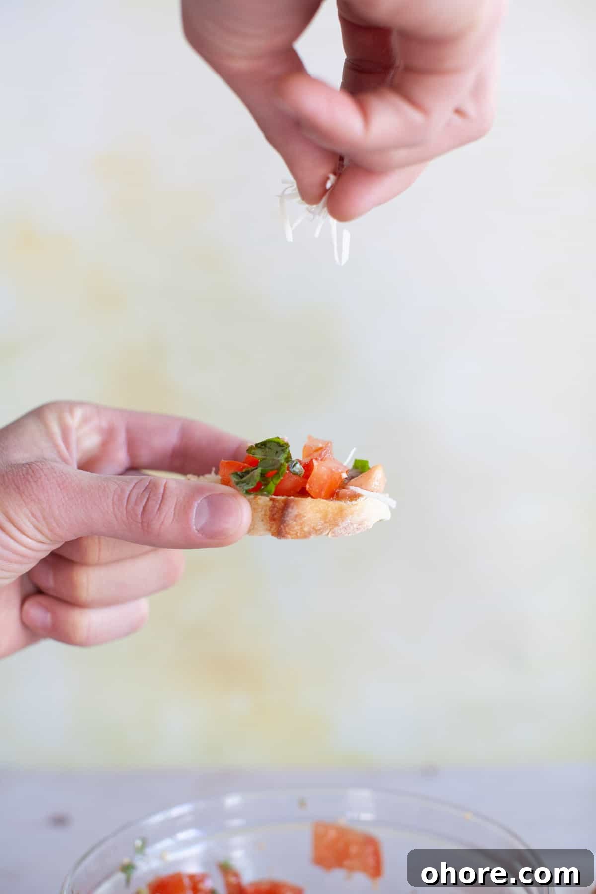 Parmesan cheese is sprinkled on top of a piece of bruschetta.