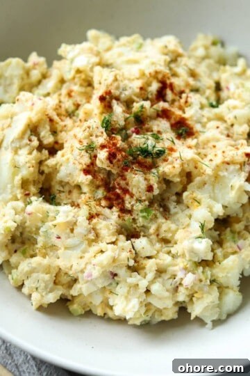 Dill pickle potato salad with paprika sprinkled on top in bowl.