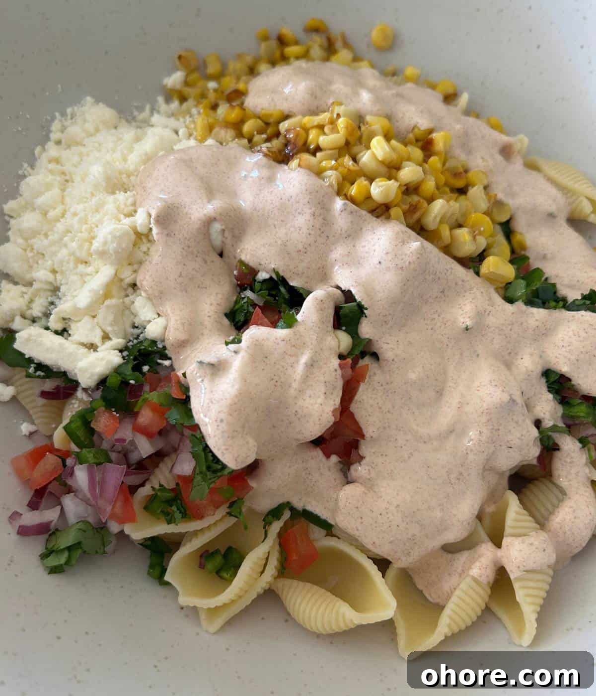 Mexican street corn salad in bowl with dressing.