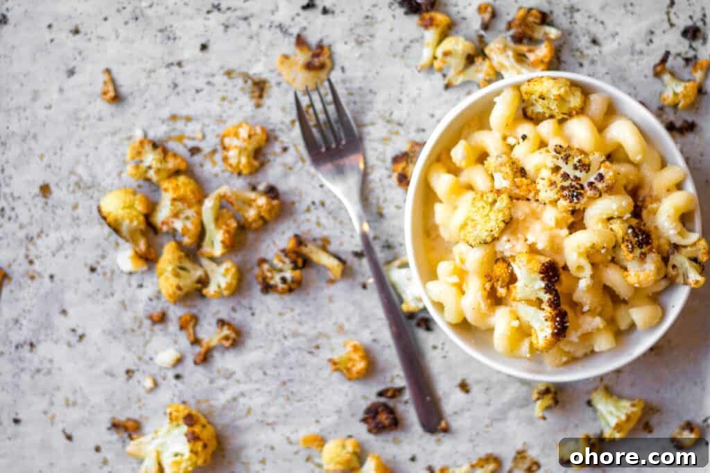 Roasted Cauliflower Mac and Cheese Casserole Recipe 2 bowl of cauliflower mac 'n cheese with roasted cauliflower on parchment paper with a silver fork