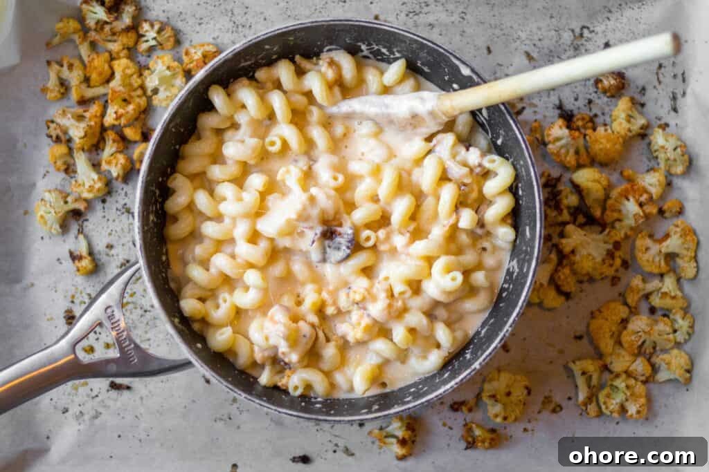 Roasted Cauliflower Mac and Cheese Casserole Recipe 6 mac 'n cheese in a black pot with roasted cauliflower on a baking sheet underneath