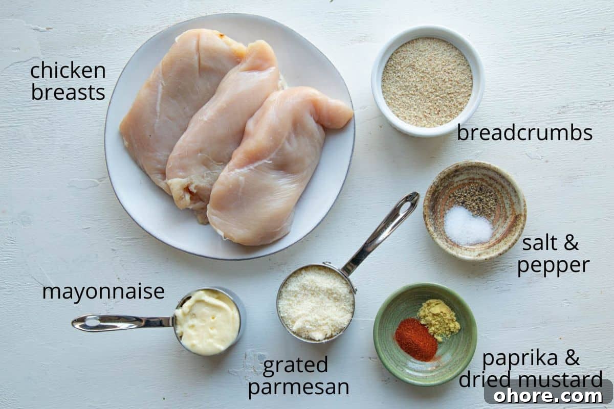 Crispy Parmesan-Crusted Baked Chicken Breast Recipe 3 chicken, parmesan, breadcrumbs, and seasonings on a white table.