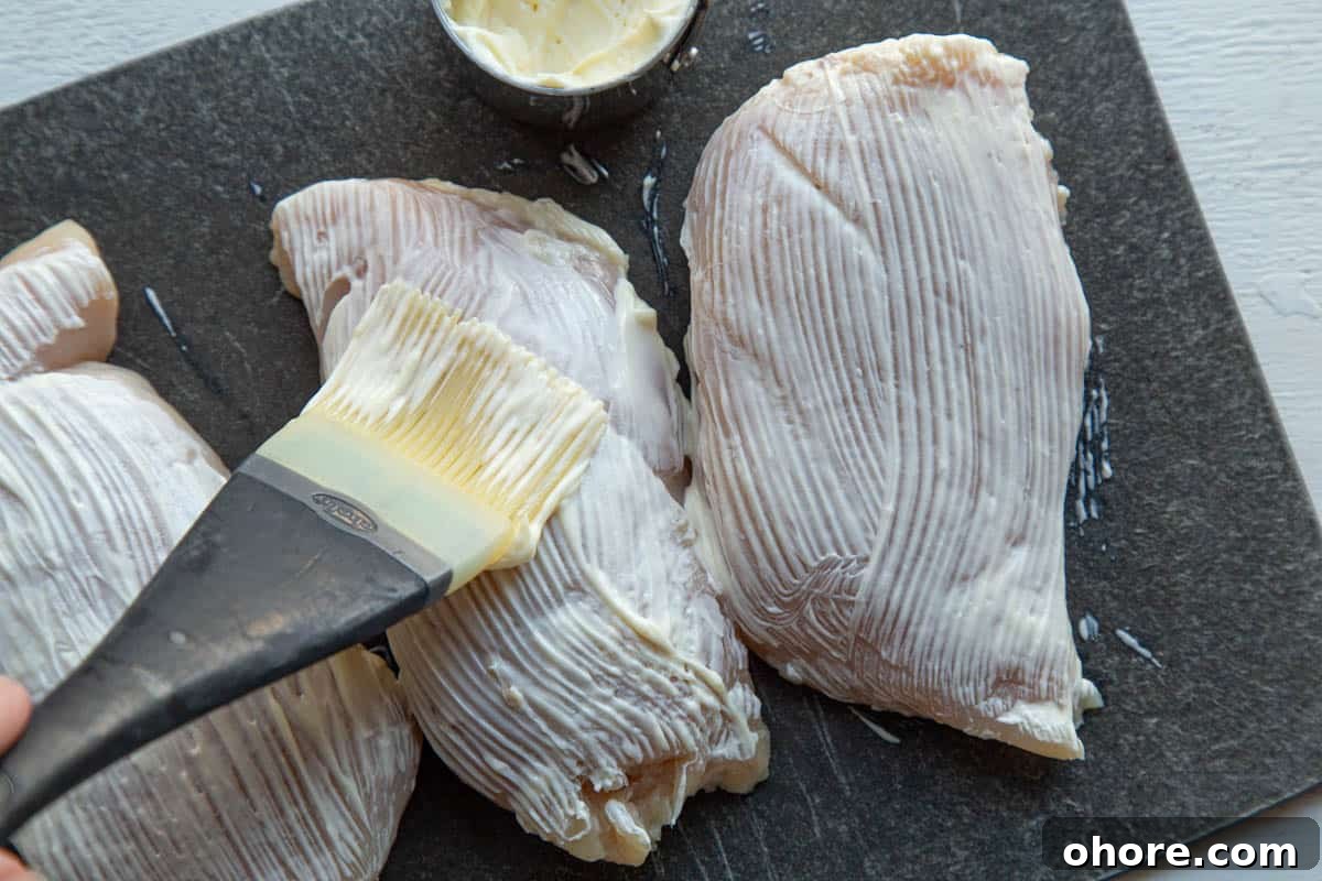 Crispy Parmesan-Crusted Baked Chicken Breast Recipe 5 brushing chicken breasts with mayonnaise using a pastry brush.