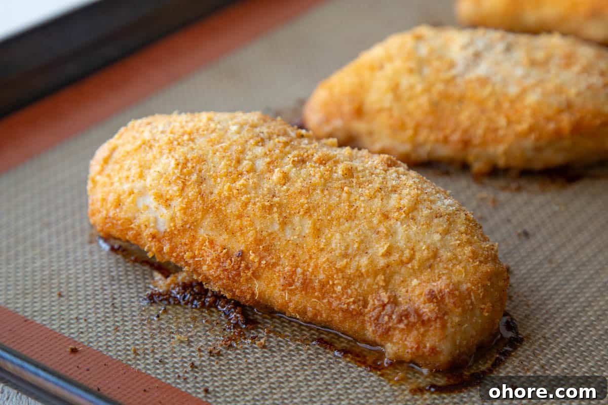 Crispy Parmesan-Crusted Baked Chicken Breast Recipe 7 baked parmesan chicken breasts on a sheet pan.