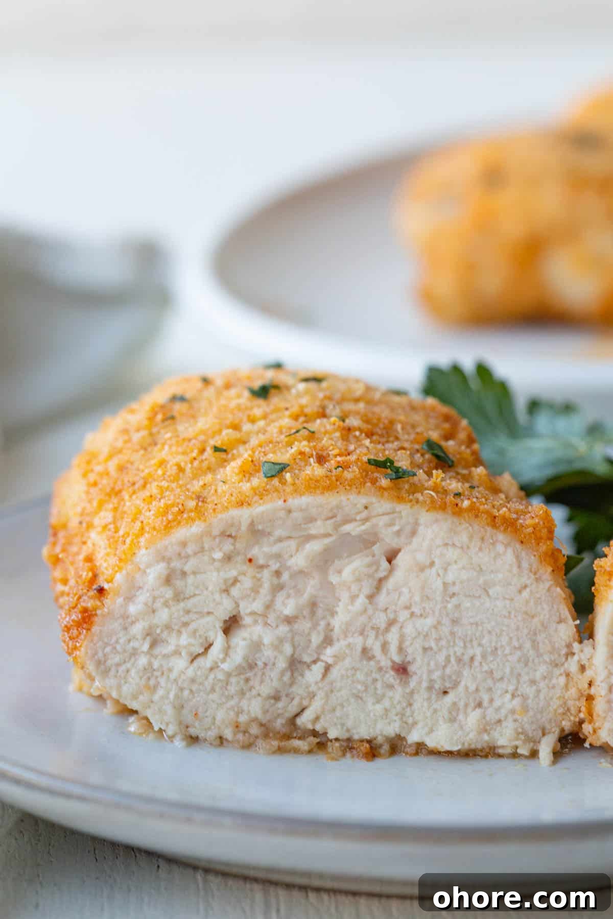 Crispy Parmesan-Crusted Baked Chicken Breast Recipe 8 the interior of a baked parmesan chicken breast on a white plate.