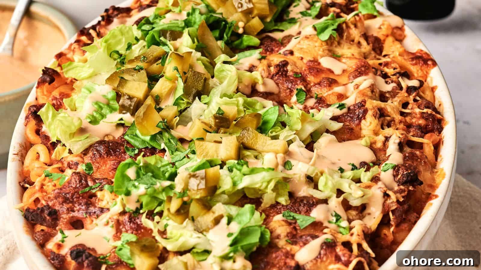 29 Cozy Air Fryer Casseroles for Warm January Dinners 18 An air fryer hamburger casserole emerges from the kitchen, a baked dish topped with melted cheese, lettuce, pickles, and sauce in a round baking dish gracing the table.