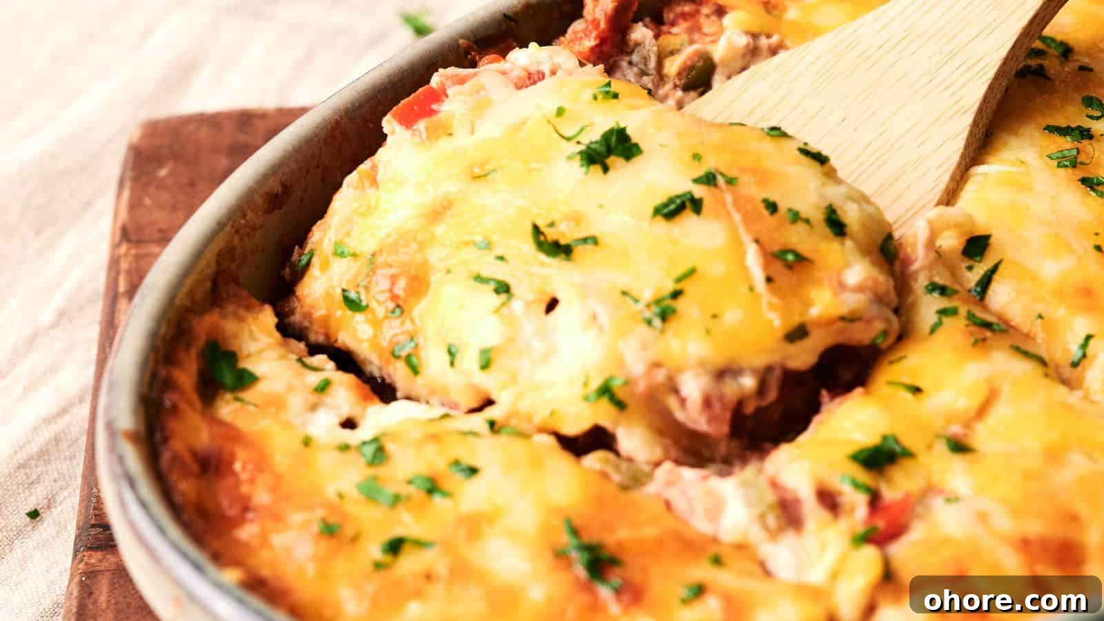 29 Cozy Air Fryer Casseroles for Warm January Dinners 22 A cheesy casserole with chopped herbs on top, being served with a wooden spatula, in a round baking dish.