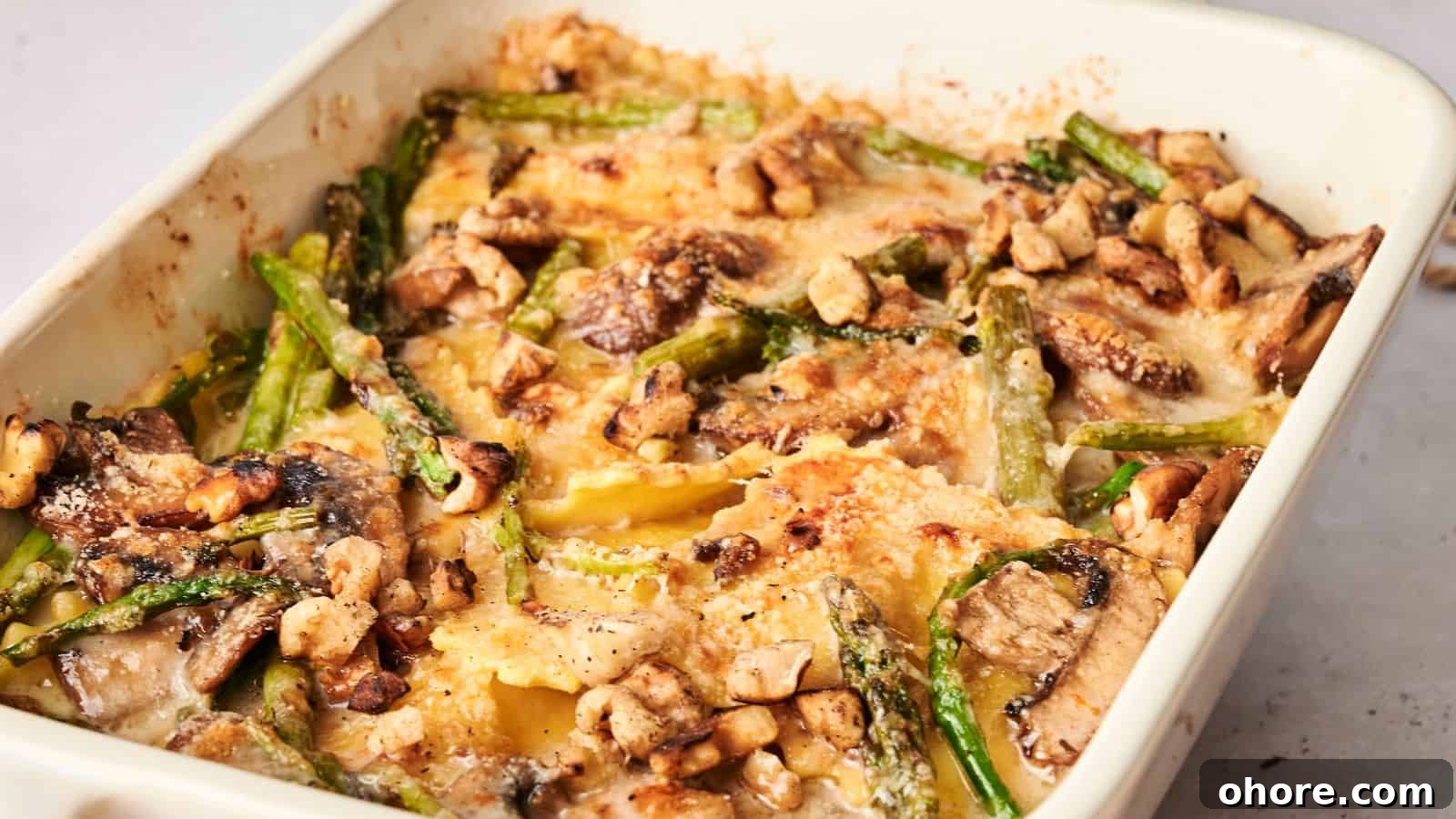 29 Cozy Air Fryer Casseroles for Warm January Dinners 23 Baked dish with layered pasta, mushrooms, asparagus, and nuts in a creamy sauce, topped with a golden-brown crust, in a rectangular white baking dish.