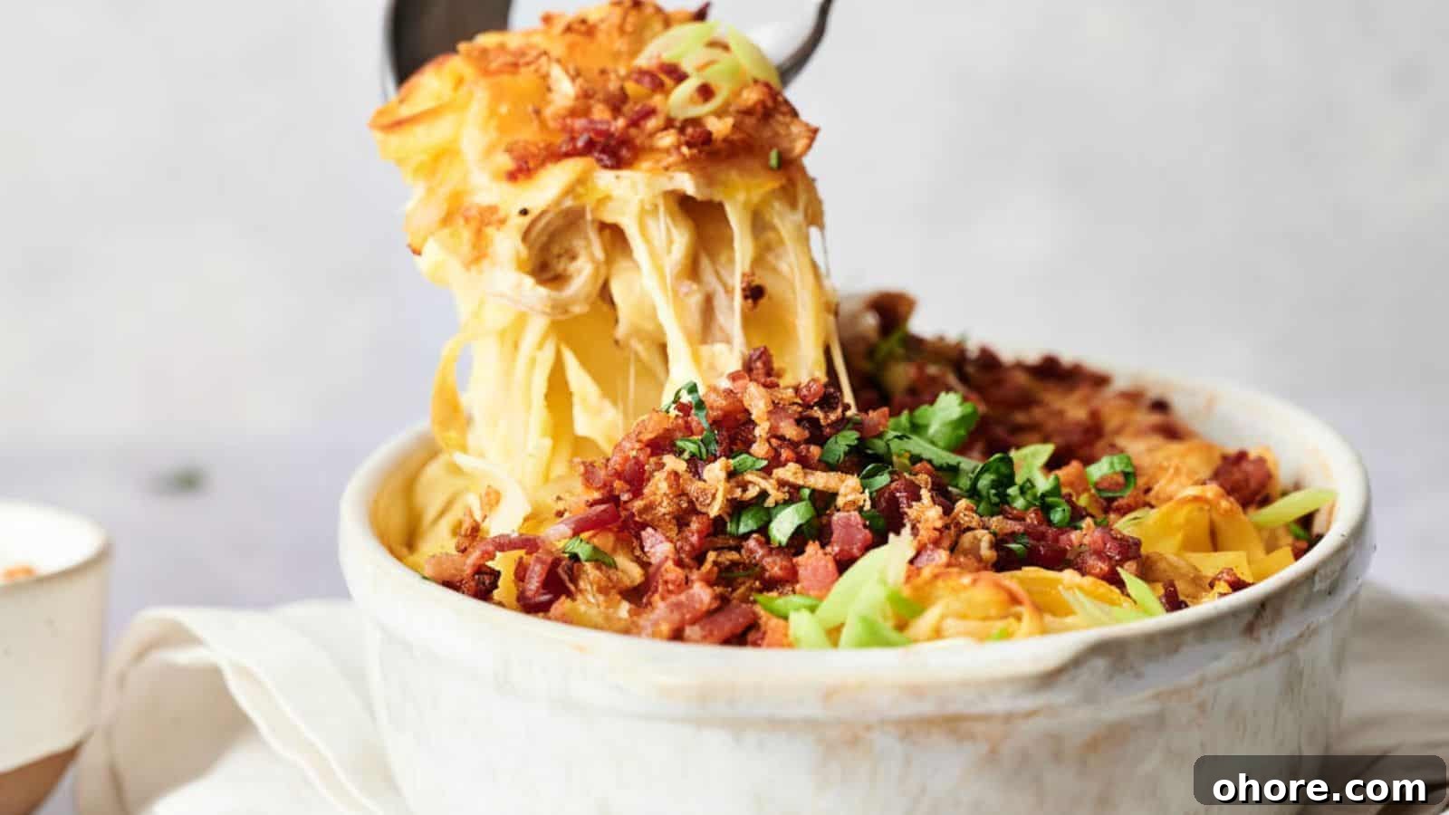 29 Cozy Air Fryer Casseroles for Warm January Dinners 5 Close-up of a casserole dish with a cheesy pasta bake, topped with crispy bacon bits and green onions. A serving spoon is lifting a portion, showing melted cheese strands.