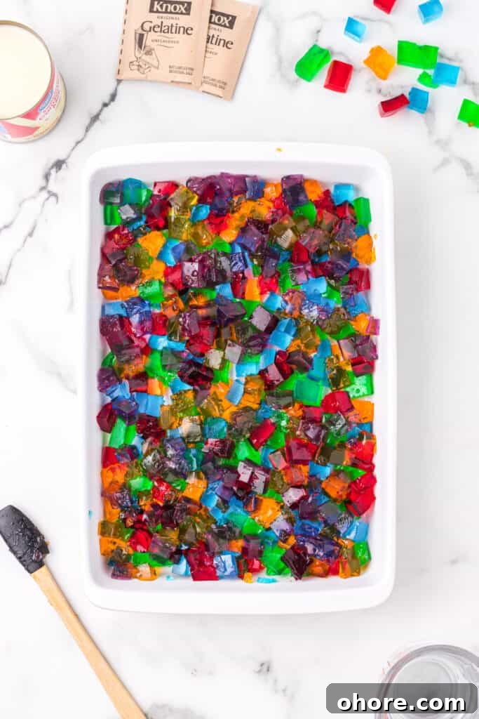 Retro Broken Glass Jello Recipe – Colorful Layered Dessert 8 Mixed colorful gelatin cubes in baking dish for Broken Glass Jello recipe with sweetened condensed milk nearby