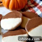 small pile of pumpkin black and white cookies with a pumpkin in the background