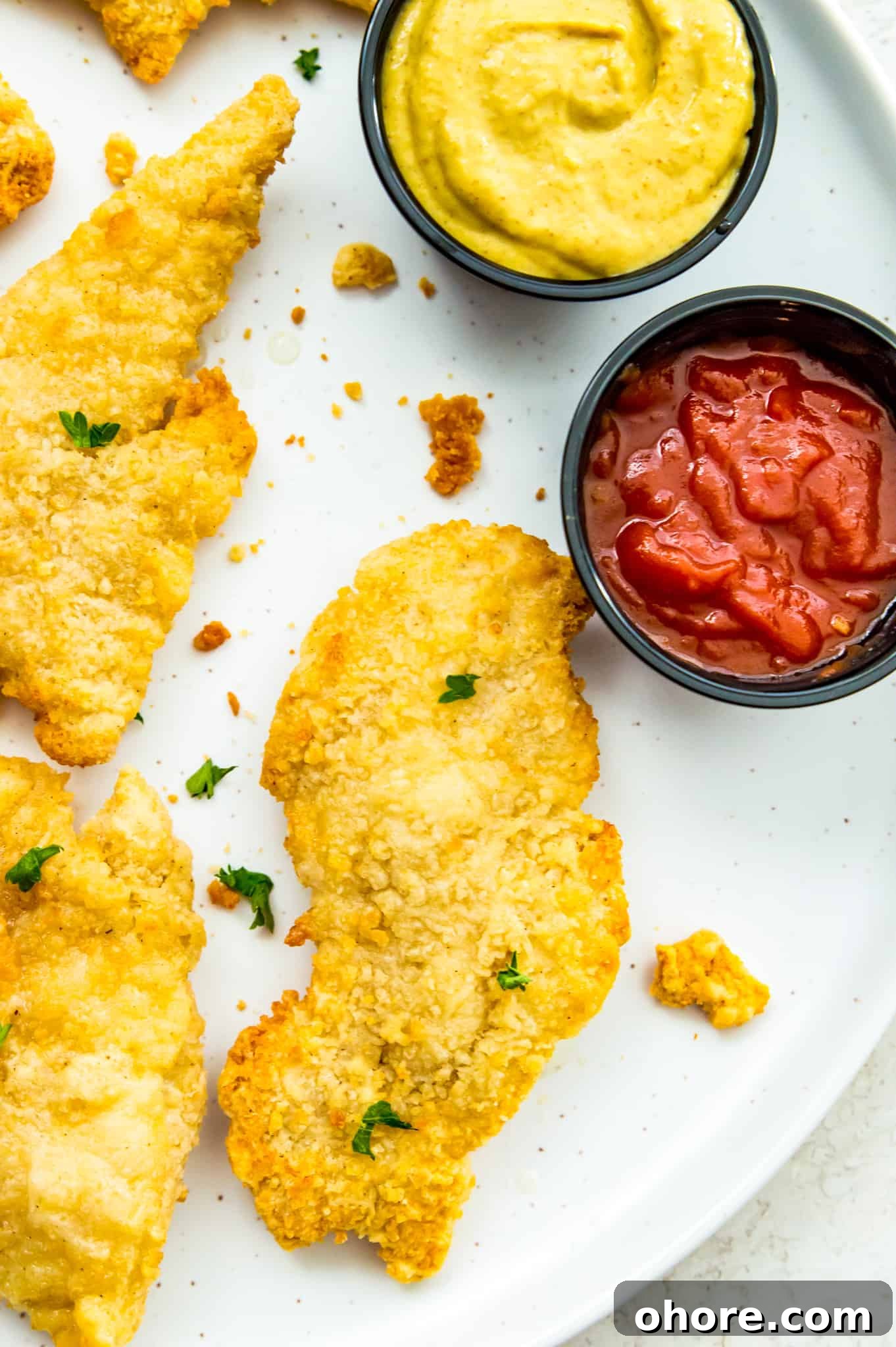 chicken tender air fryer recipe A plate of cooked chicken tenders with a dish of ketchup beside them.