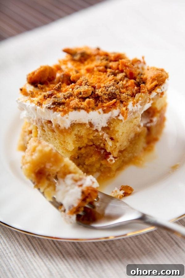 a slice of butterfinger poke cake with one bite taken out of it.