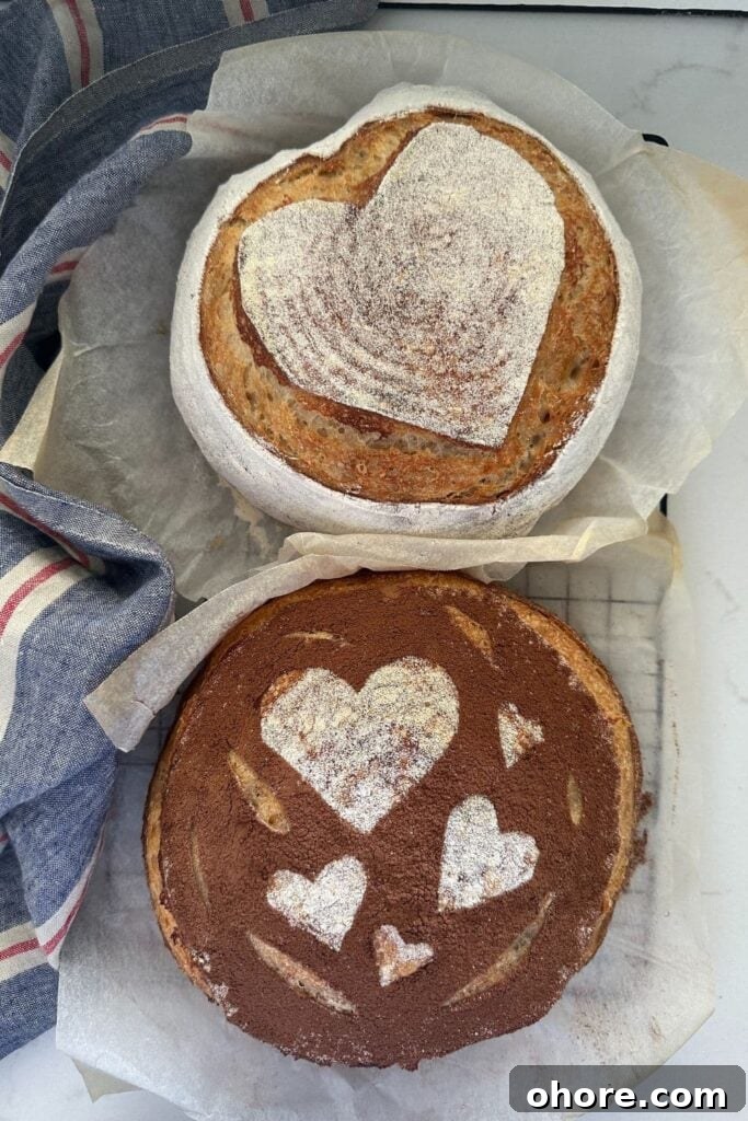 Sourdough Recipes for a Romantic Valentine’s Day Meal 3 Two loaves of sourdough bread for Valentine's Day. The top one has a white heart scored into it and the bottom one has white hearts stencilled on surrounded by cocoa powder.