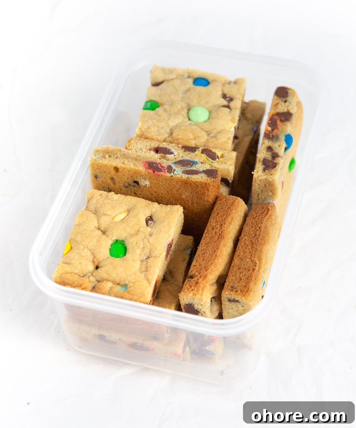 Chewy M&M Cookie Bars Recipe — Loaded Candy Cookie Bars 9 Chewy M&M Cookie bars cut into squares in plastic container for freezing