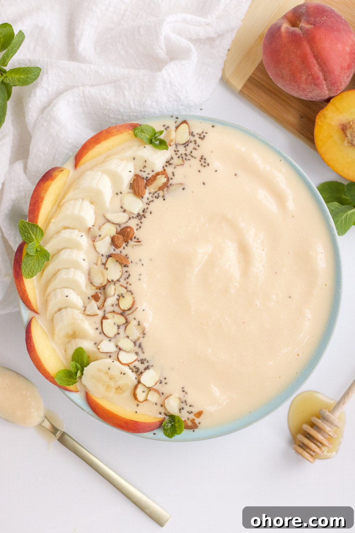 peach smoothie bowl with fresh fruit and nut toppings
