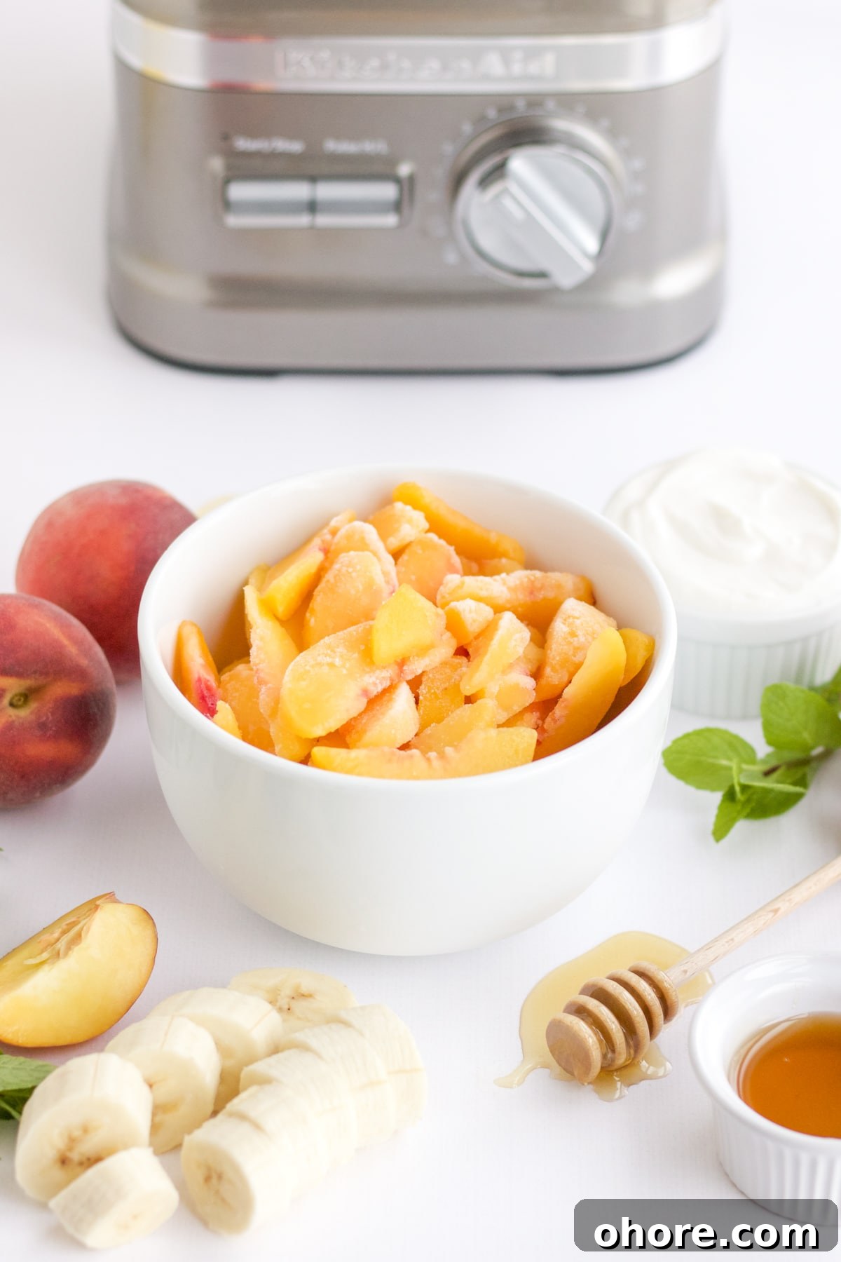 frozen peaches in a white bowl with a bananas, honey and yogurt