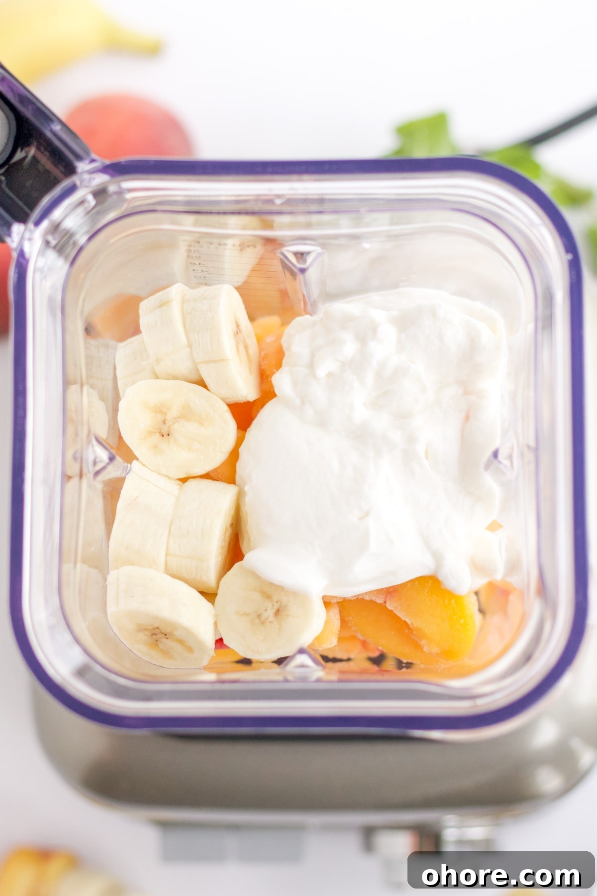 overhead shot of ingredients in a blender: bananas, yogurt and peaches