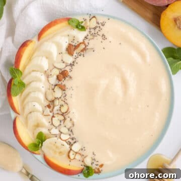 peach smoothie bowl with fresh fruit and nut toppings