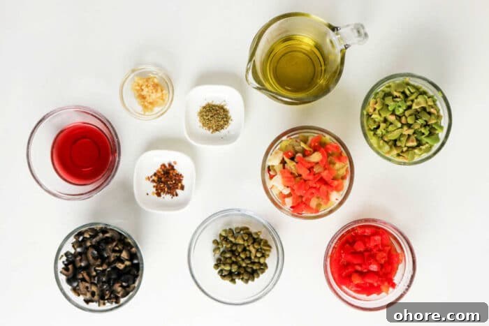 Authentic Muffuletta Olive Salad Recipe for Classic Sandwiches 3 Various small bowls with chopped vegetables, olives, capers, spices, oil, and vinegar arranged on a white surface—perfect ingredients for a classic Muffuletta recipe or homemade olive salad.