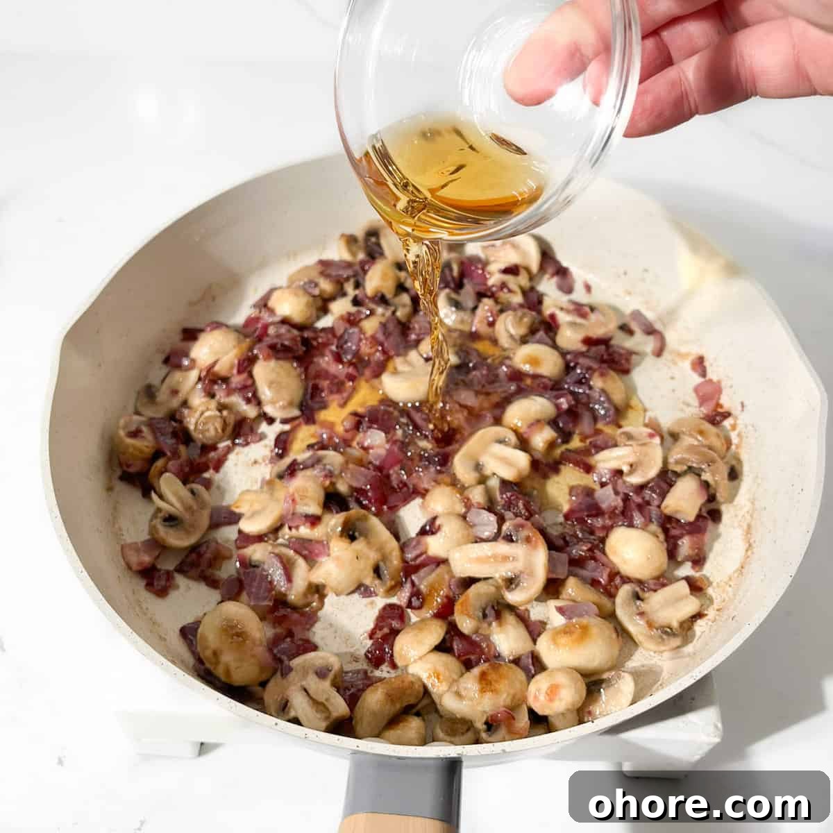 Adding the whiskey to the onions for the creamy steak pasta.