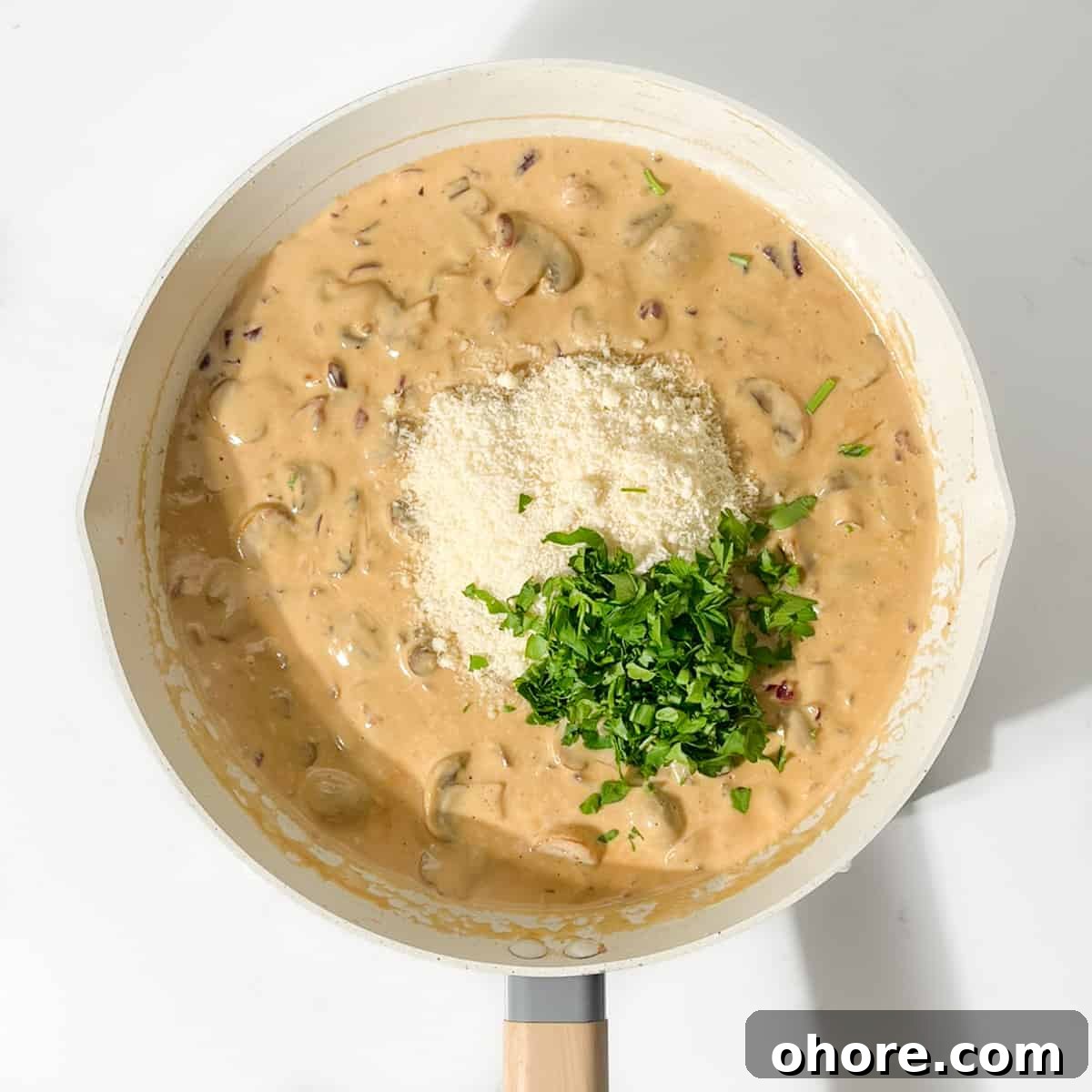 Adding parmesan and parsley to the sauce for the creamy steak pasta.