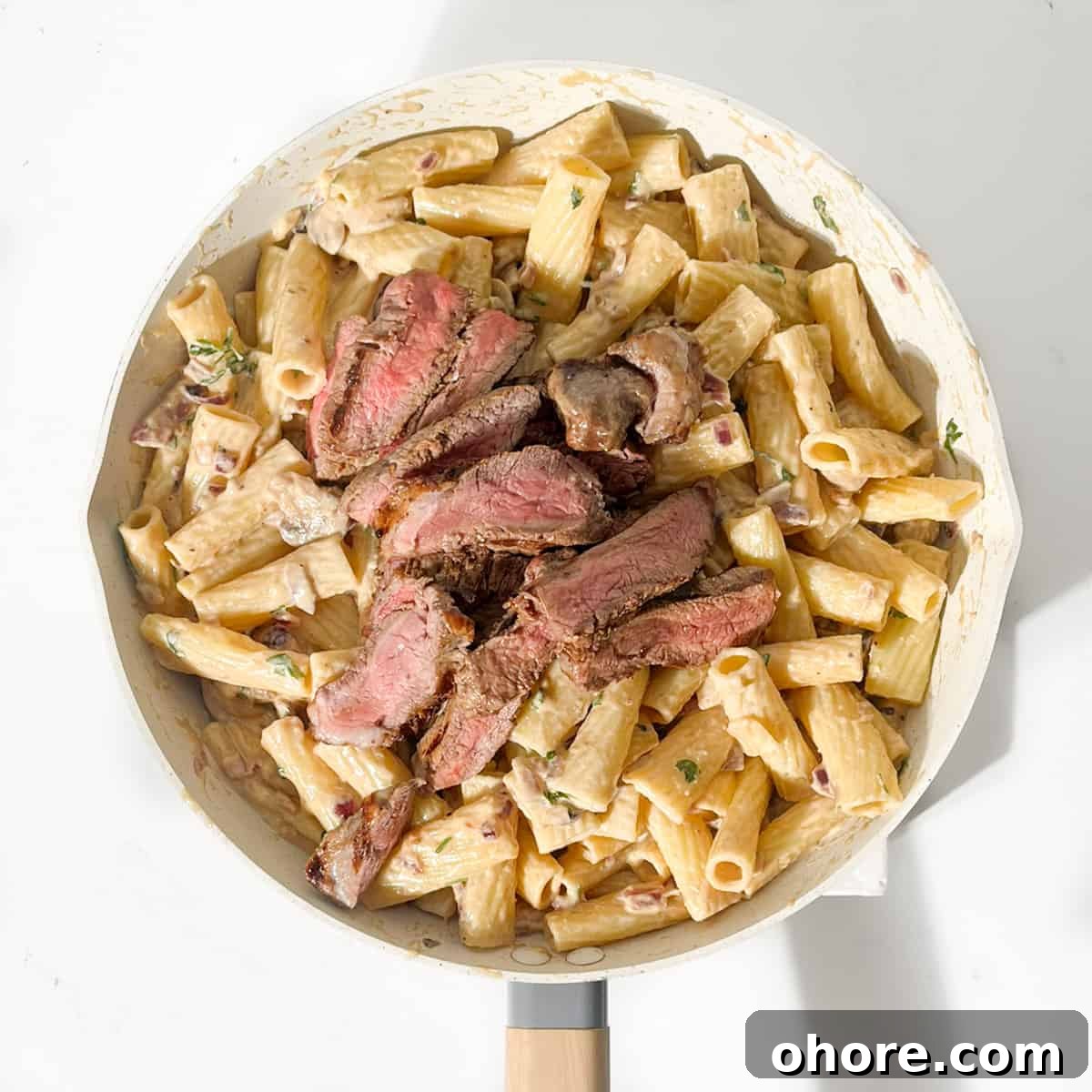 Adding the steak to the pasta.