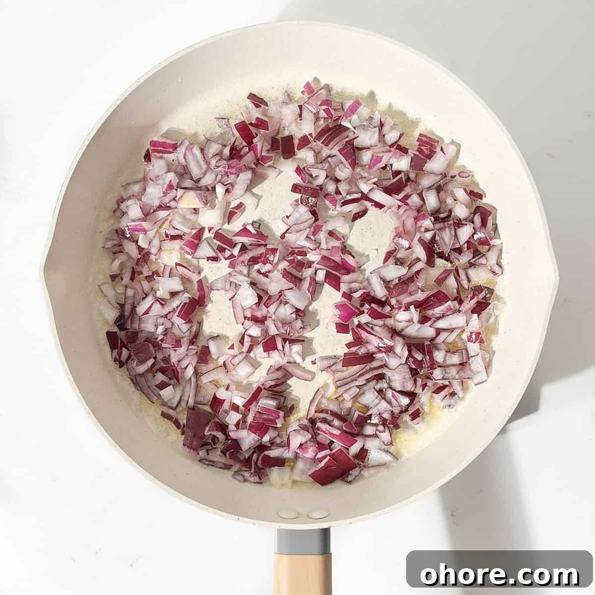Frying onions for the creamy steak pasta in a large frying pan.