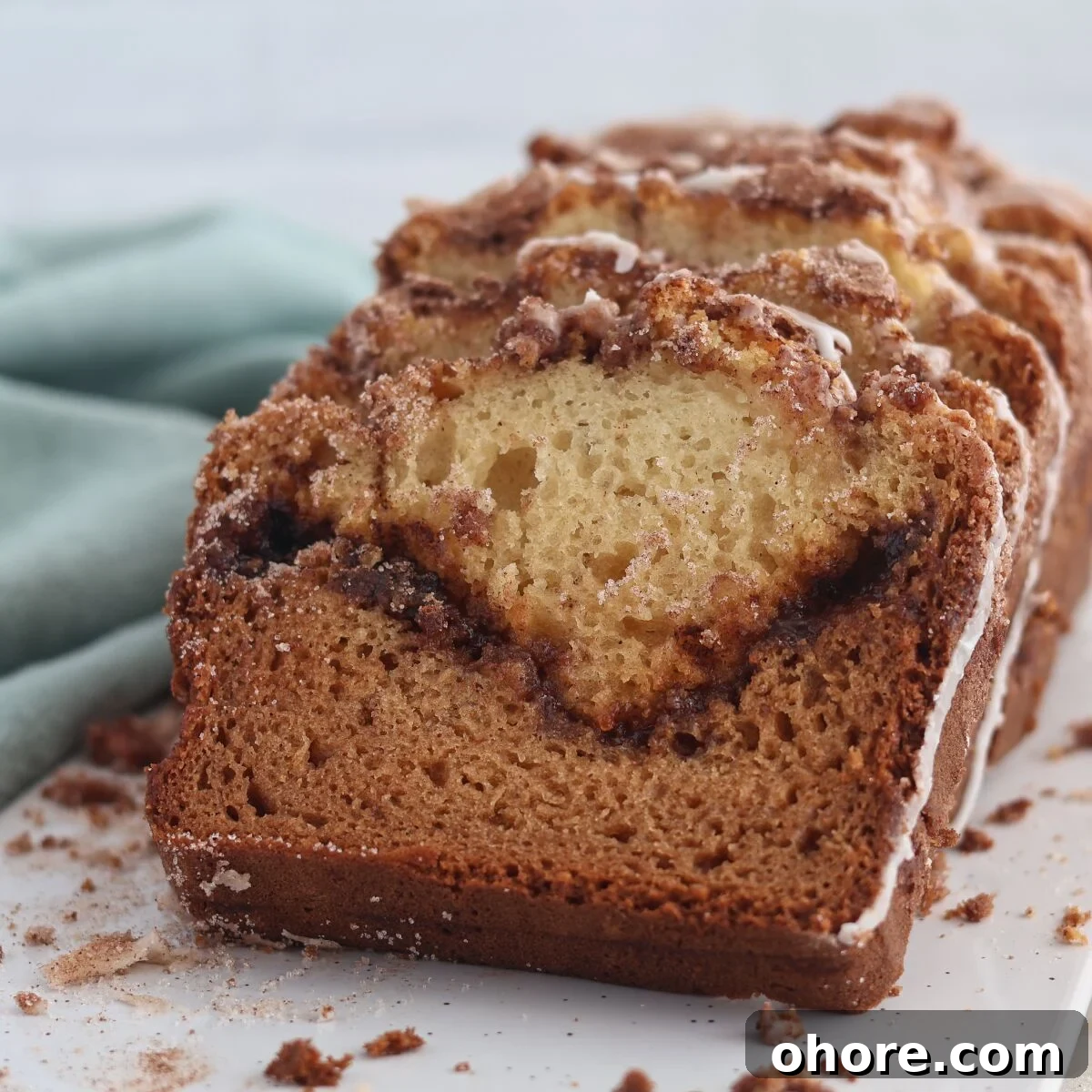 sliced cinnamon swirl quick bread with seafoam green towel alongside.