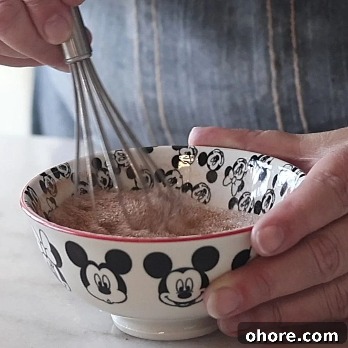 whisking together cinnamon and sugar in small mickey mouse bowl.