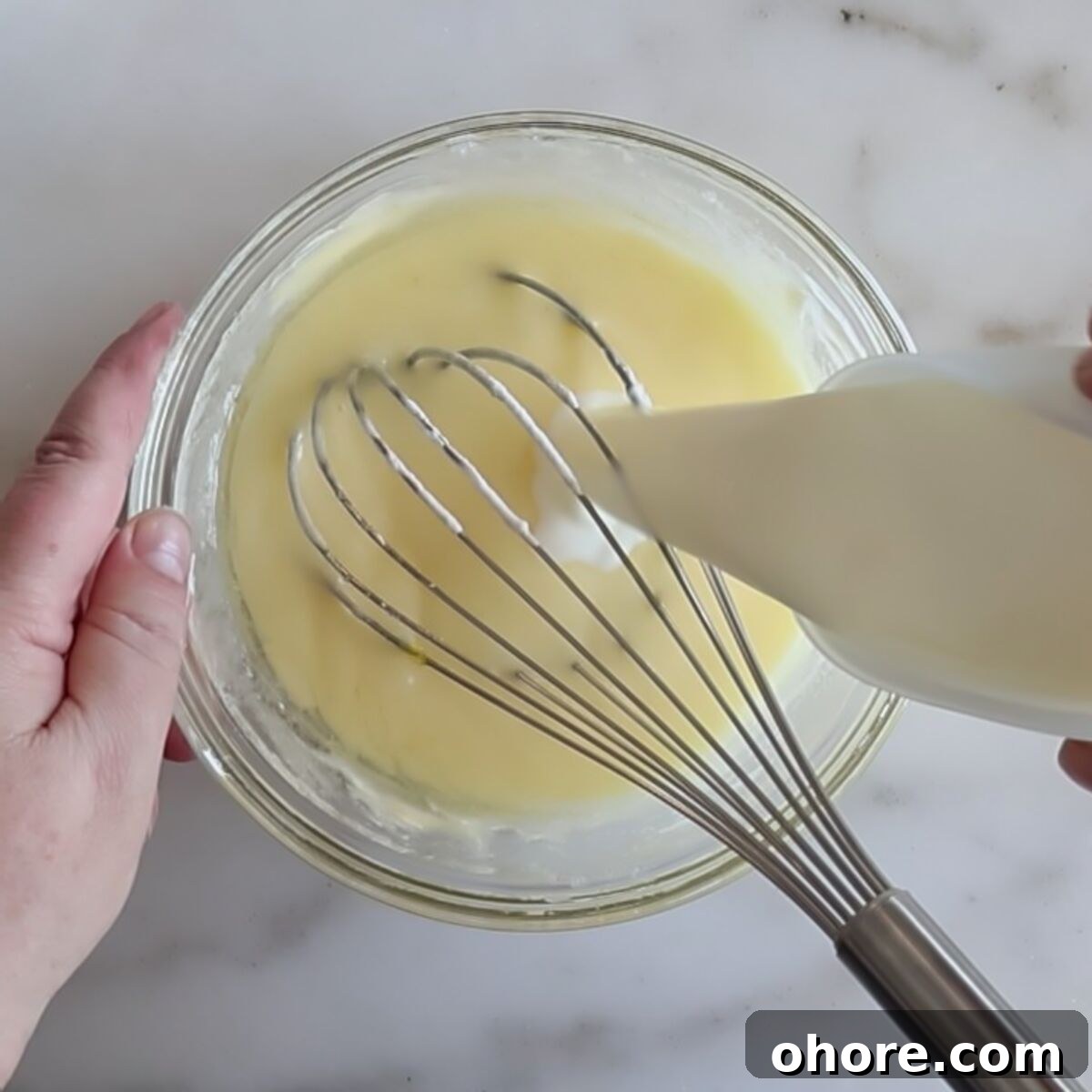 pouring milk into egg/sugar mixture in small glass bowl.