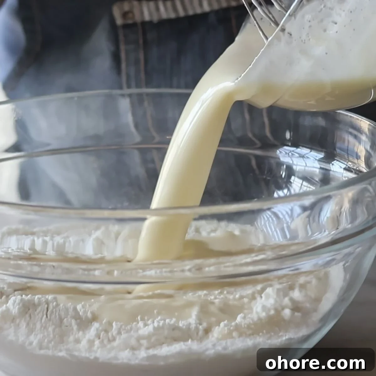 pouring wet ingredients into dry ingredients in large glass bowl.