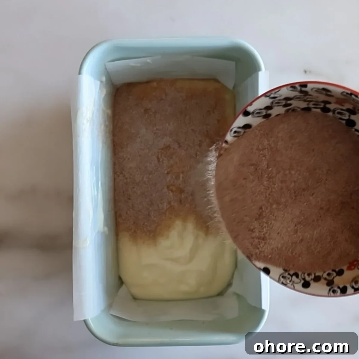 sprinkling cinnamon sugar over half of batter in light blue loaf pan.