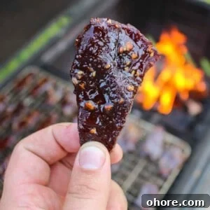 Spicy Honey Garlic Beef Jerky Recipe for Homemade Snacks 9 A piece of Hot Honey Garlic Beef Jerky held up close to the camera.