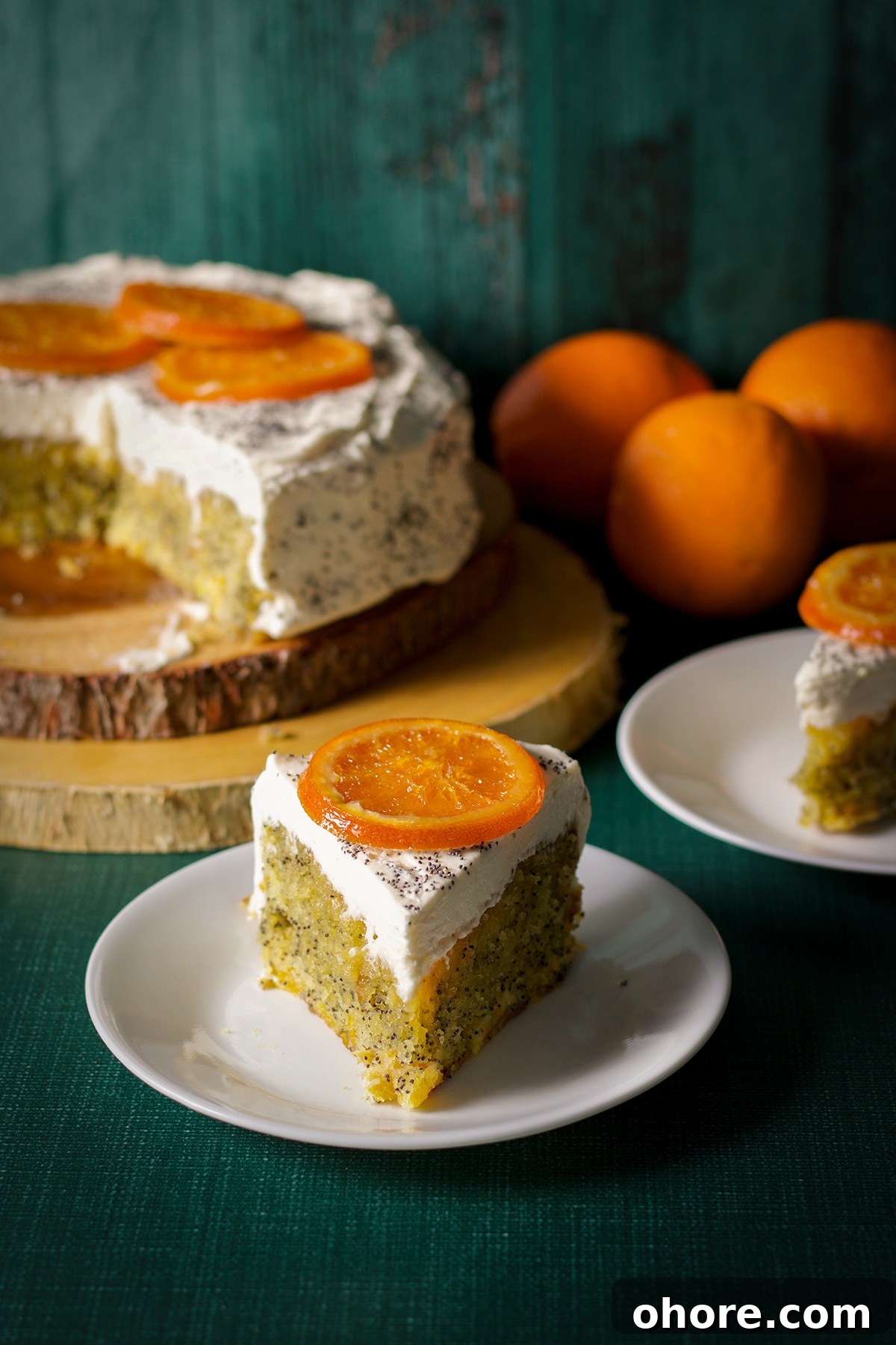 Orange Poppy Seed Cake with Mascarpone Frosting Recipe 2 A slice of orange poppy seed cake with mascarpone frosting decorated with a candied orange slice.