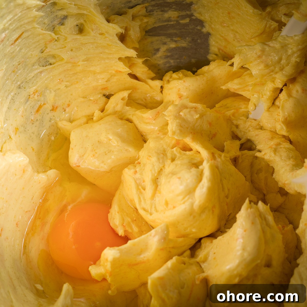 Orange Poppy Seed Cake with Mascarpone Frosting Recipe 12 Cracking an egg into cake batter.