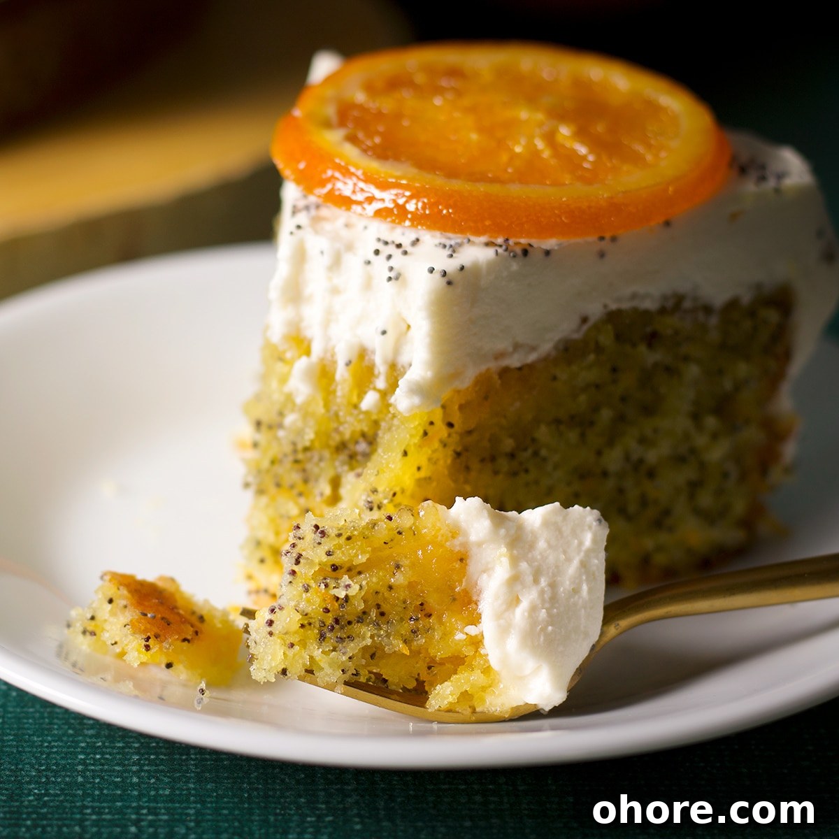 Orange Poppy Seed Cake with Mascarpone Frosting Recipe 6 A slice of orang poppy seed cake on a plate with a bite taken out of it.