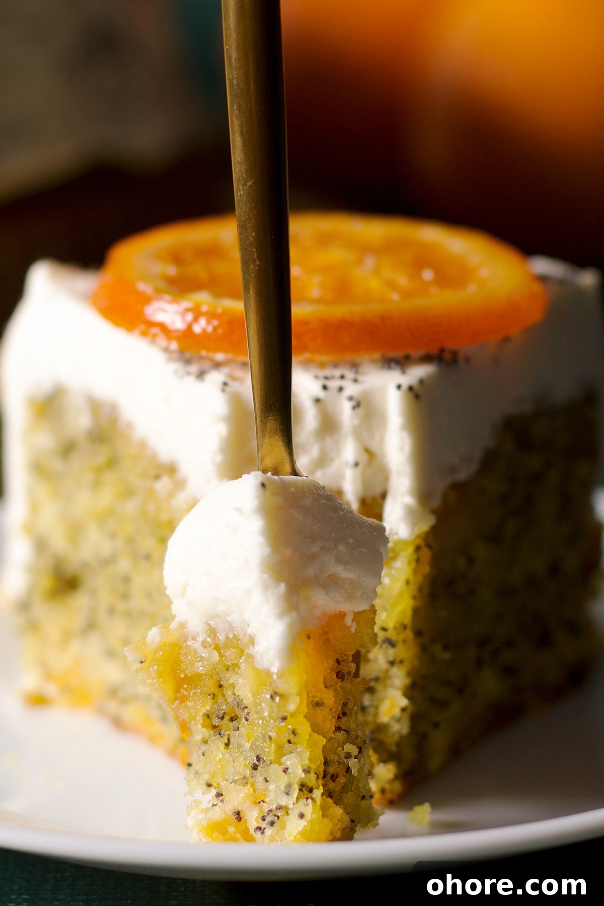 Orange Poppy Seed Cake with Mascarpone Frosting Recipe 22 Poking a fork into a slice of orange poppy seed cake to cut a bite.