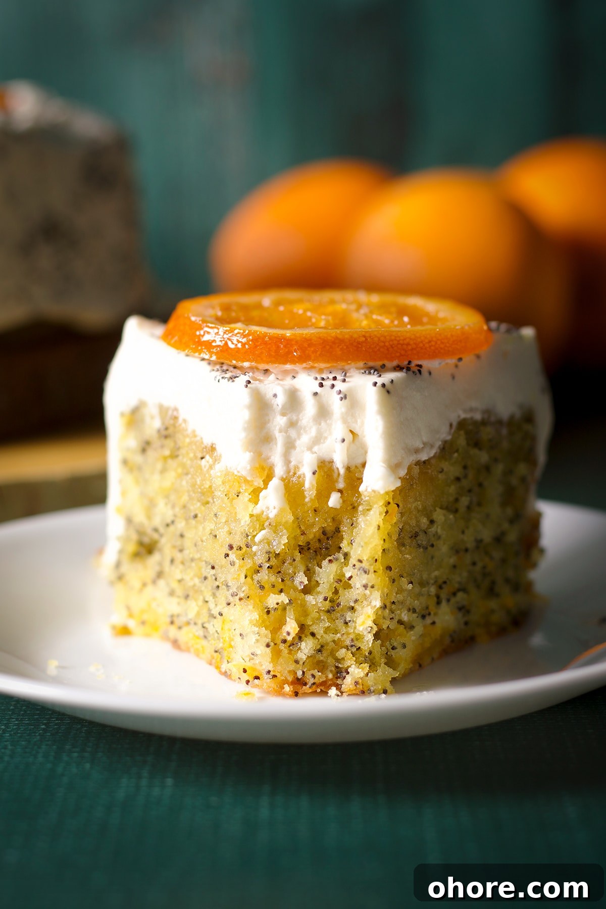 Orange Poppy Seed Cake with Mascarpone Frosting Recipe 23 A slice of orang poppy seed cake on a plate with a bite taken out of it.