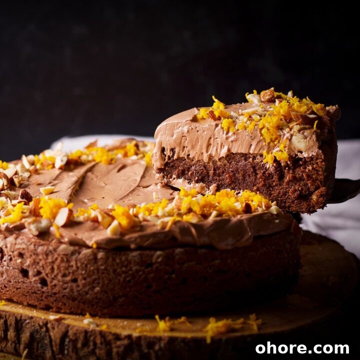 Someone using a cake server to lift a slice of chocolate almond cake from the whole cake.