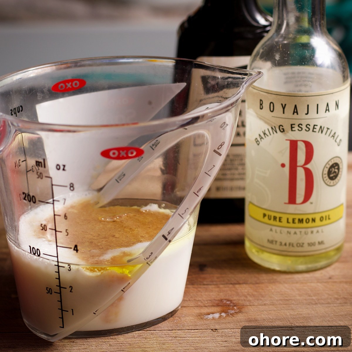 Orange Poppy Seed Cake with Mascarpone Frosting Recipe 5 A measuring cup filled with buttermilk, vanilla extract, and lemon oil.