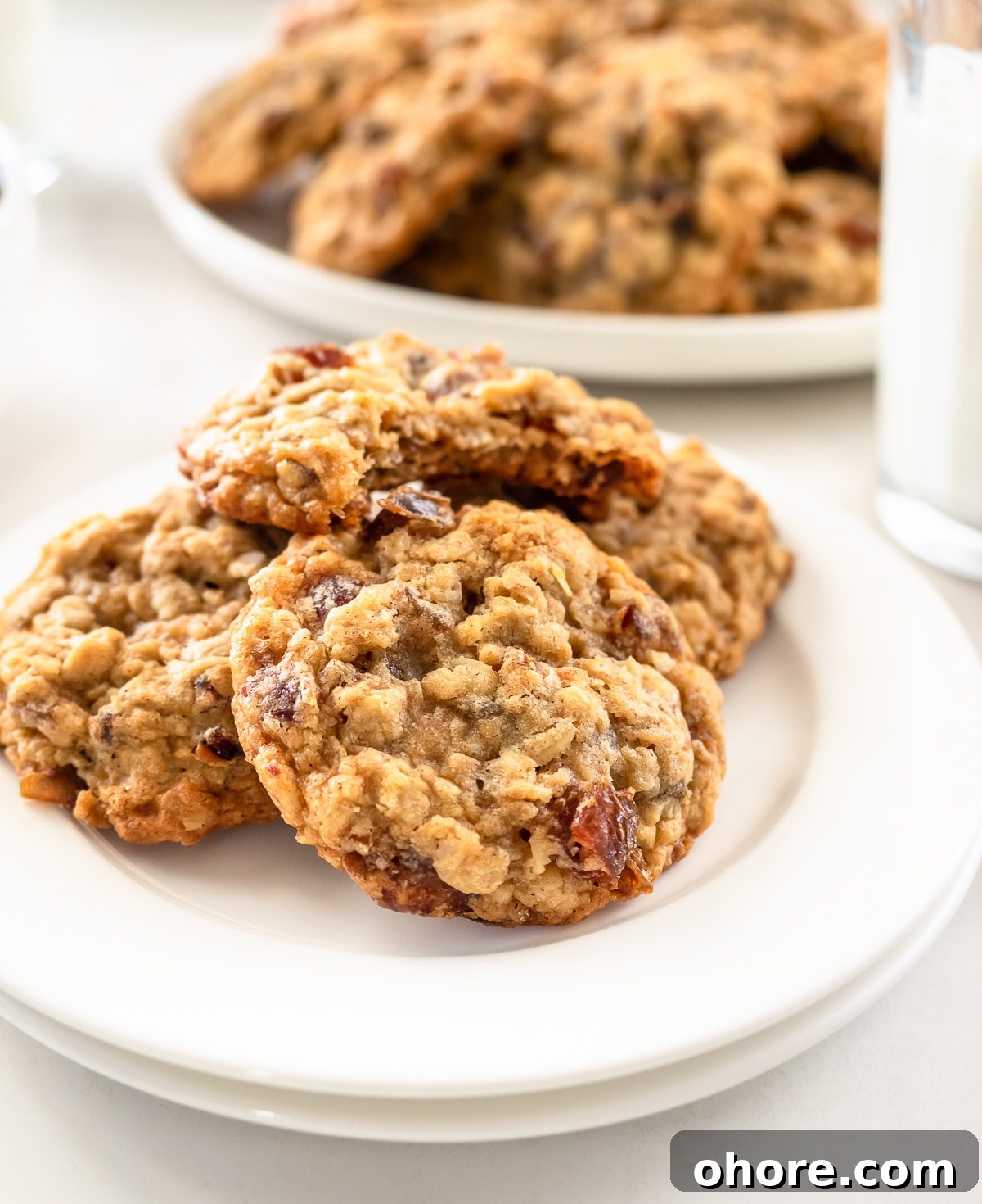 Chewy Oatmeal Cookies with Sweet Dates 2 Oatmeal cookies with dates on small white dish.