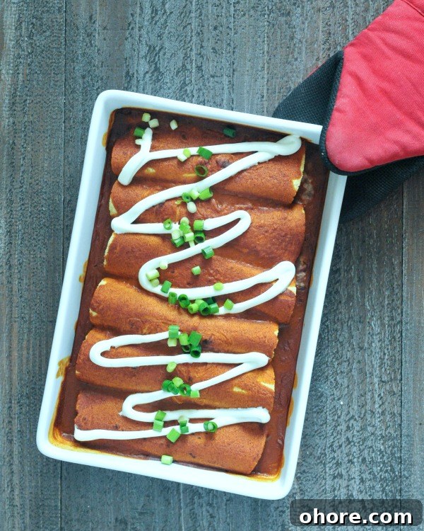 Bean and Cauliflower Rice Enchiladas overhead view of Easy Bean and Cauliflower Rice Enchiladas in a white rectangle ceramic baking dish held by a red oven glove